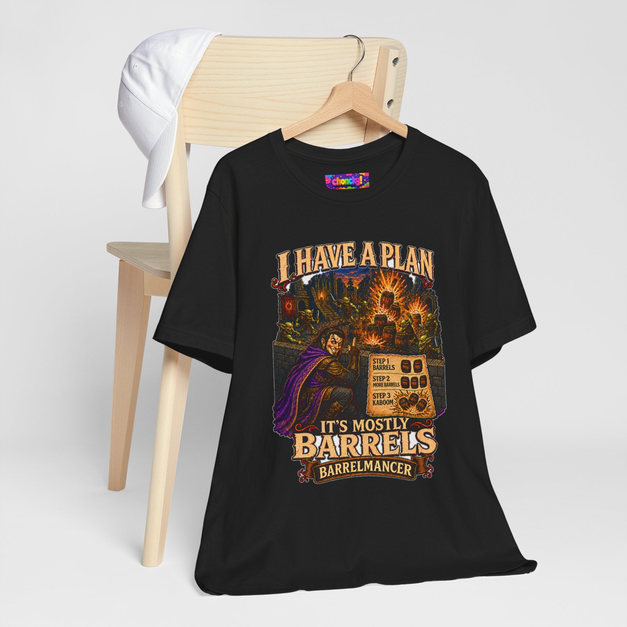 I Have a Plan Barrelmancer fantasy RPG graphic T-shirt, black shirt hanging beside a chair.