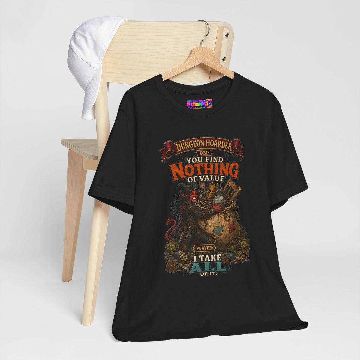 Dungeon Hoarder tiefling tabletop RPG graphic T-shirt, black shirt hanging beside a chair.