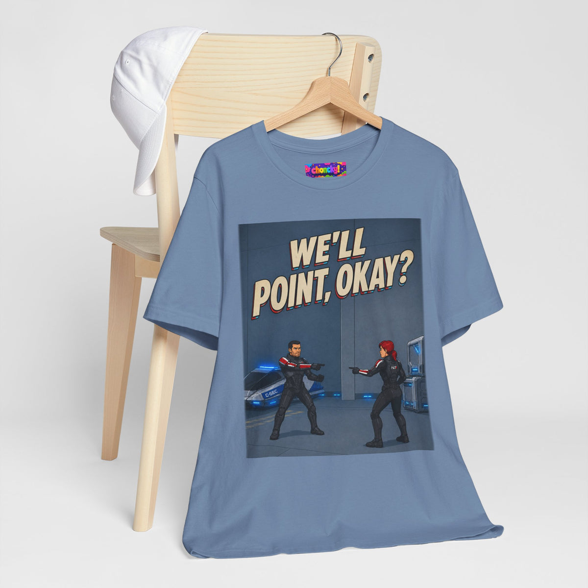 We'll Point, Okay? retro sci-fi action graphic T-shirt, blue shirt hanging from a wooden hanger beside a chair.